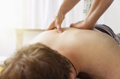 Young man gets a massage for pain in his back